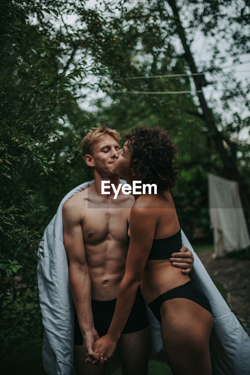 Young couple standing against trees