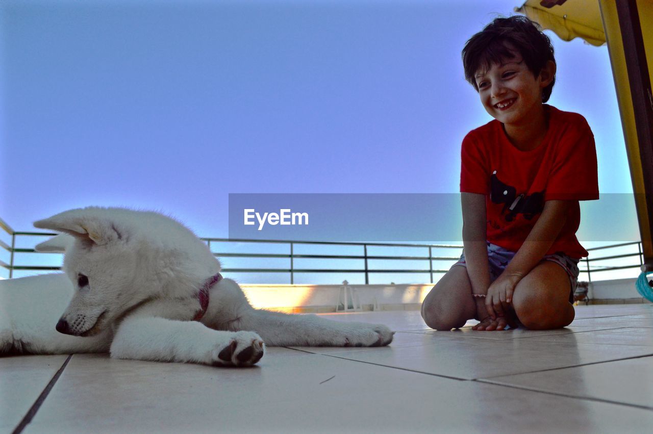 Side view of kid with dog on floor