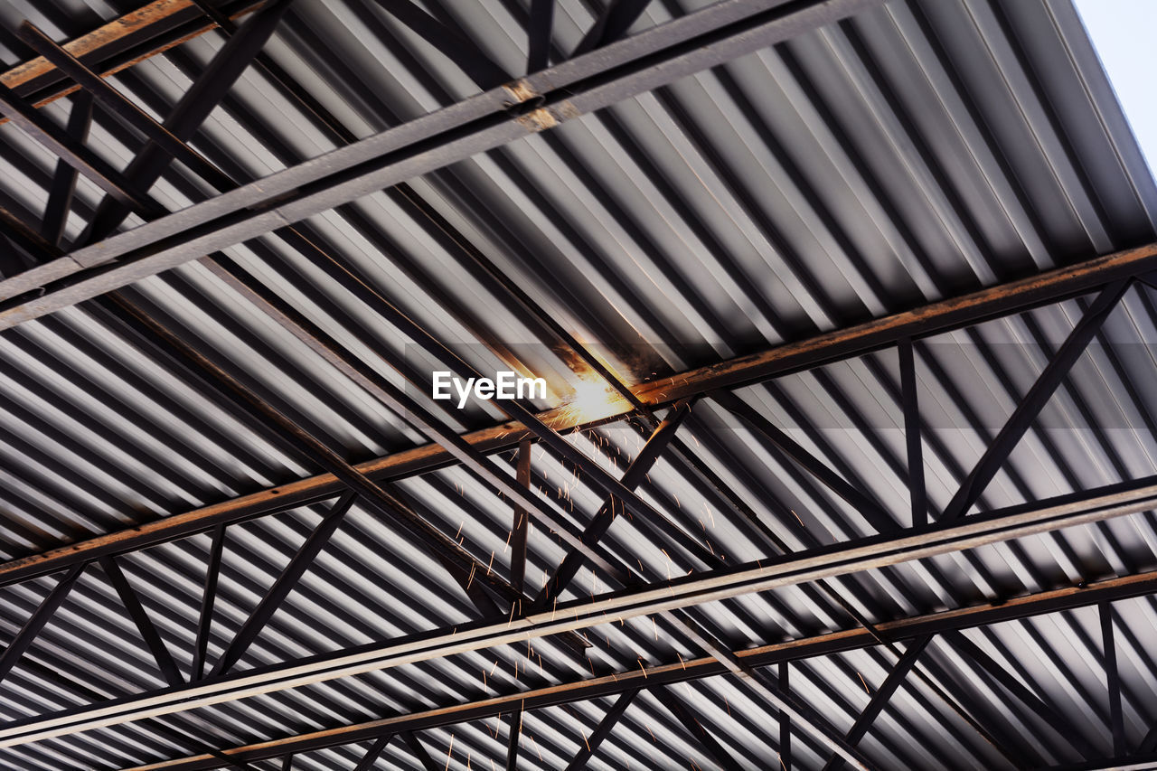 Low angle view of sparks emitting from girders at construction site