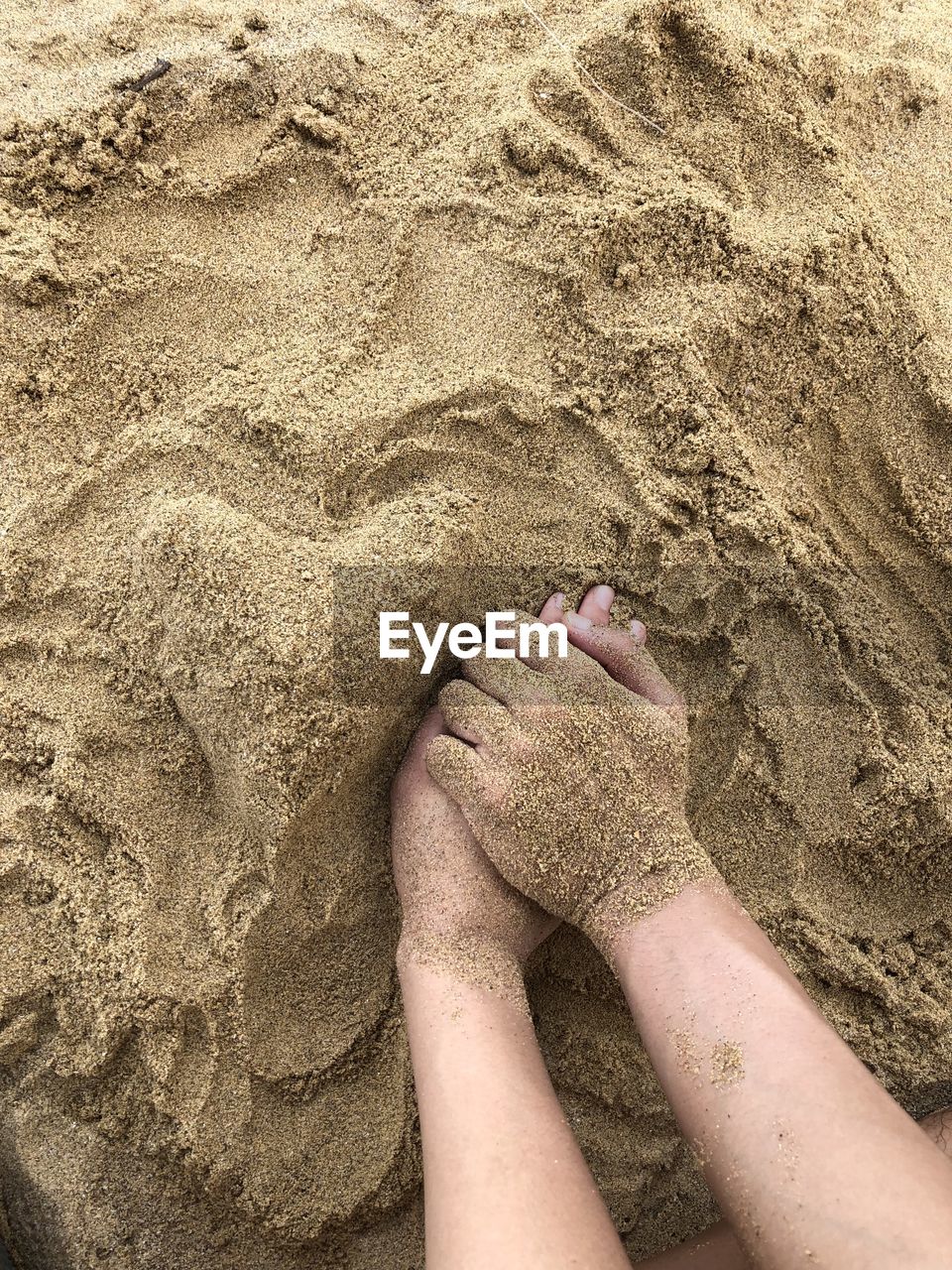 Cropped image of hands on sand