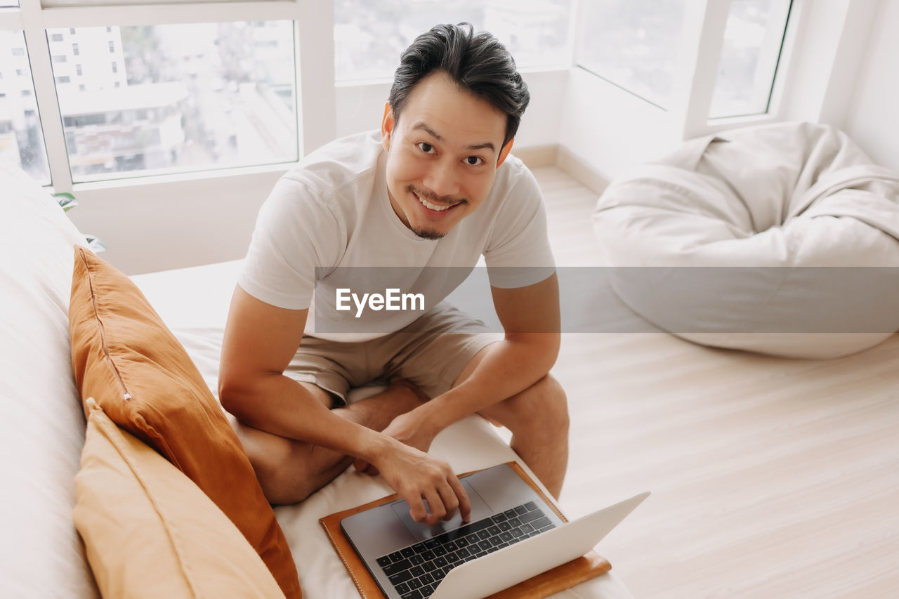 Portrait of smiling man using laptop at home