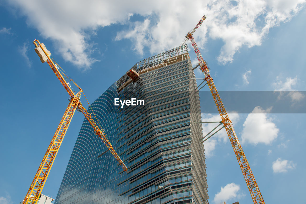 LOW ANGLE VIEW OF CRANES AT CONSTRUCTION SITE AGAINST SKY