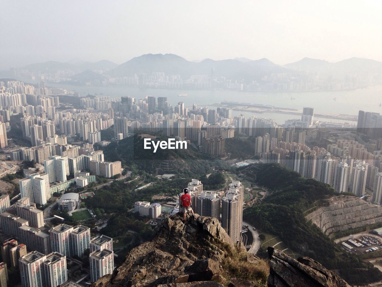 Man on top of peak with city in background