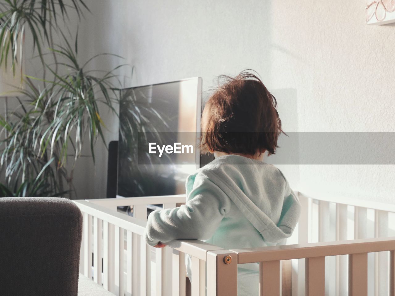 Rear view of child standing on chair at home