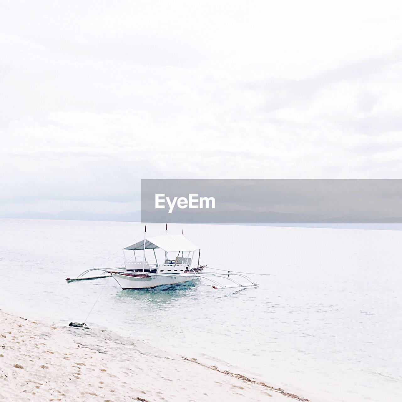 Outrigger boat in sea against cloudy sky