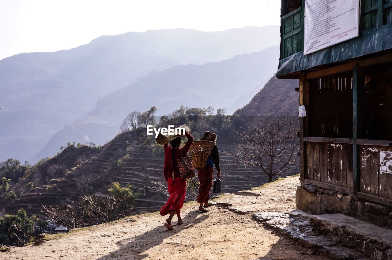 Rear view of woman walking on road against mountains