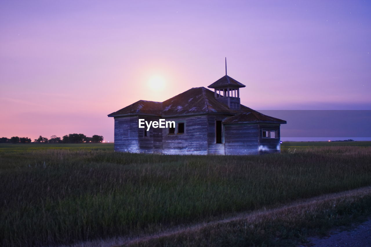 House on field against sky during sunset