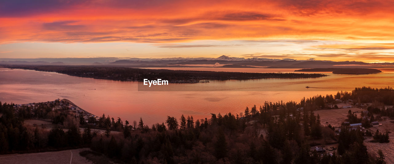 sky, sunset, environment, landscape, scenics - nature, cloud, tree, beauty in nature, nature, dawn, water, plant, evening, land, sun, tranquility, mountain, forest, travel, travel destinations, no people, tranquil scene, coniferous tree, lake, dramatic sky, pinaceae, outdoors, tourism, orange color, twilight, pine tree, cold temperature, sunlight, fog, city, afterglow, multi colored, winter, pine woodland, panoramic, idyllic, architecture, vacation, wilderness, high angle view, holiday, red, woodland