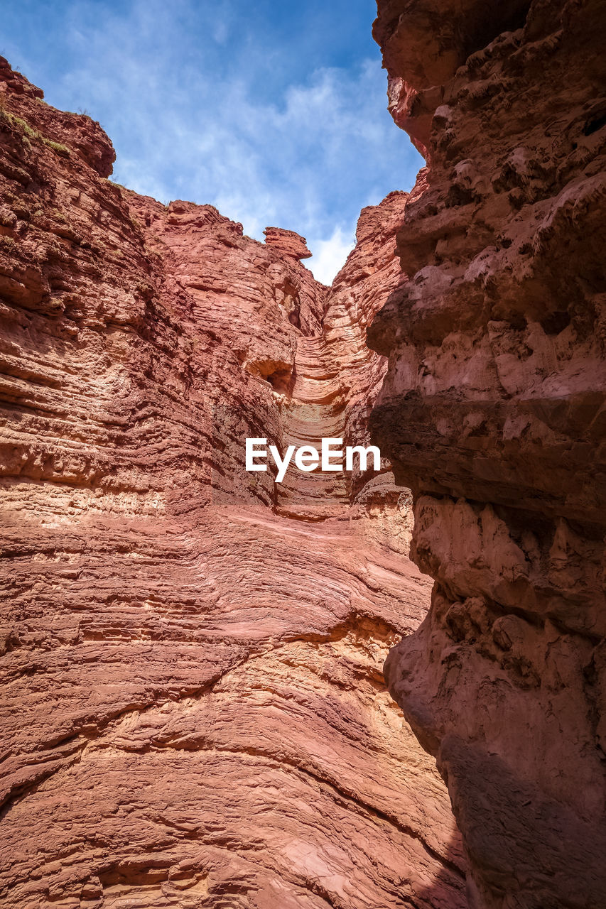 LOW ANGLE VIEW OF ROCK FORMATION AGAINST CLOUDY SKY