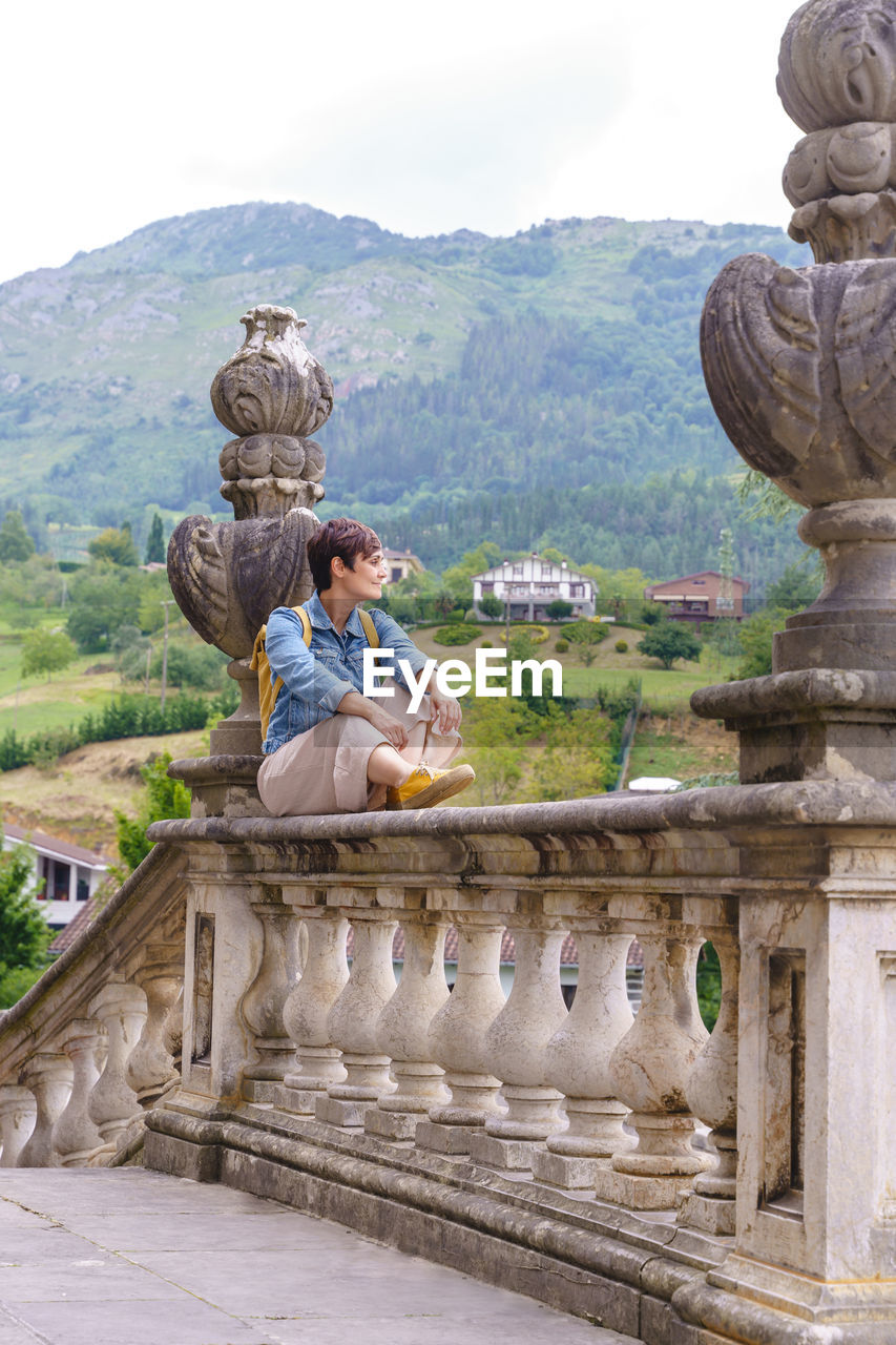 rear view of woman standing by statue against mountain