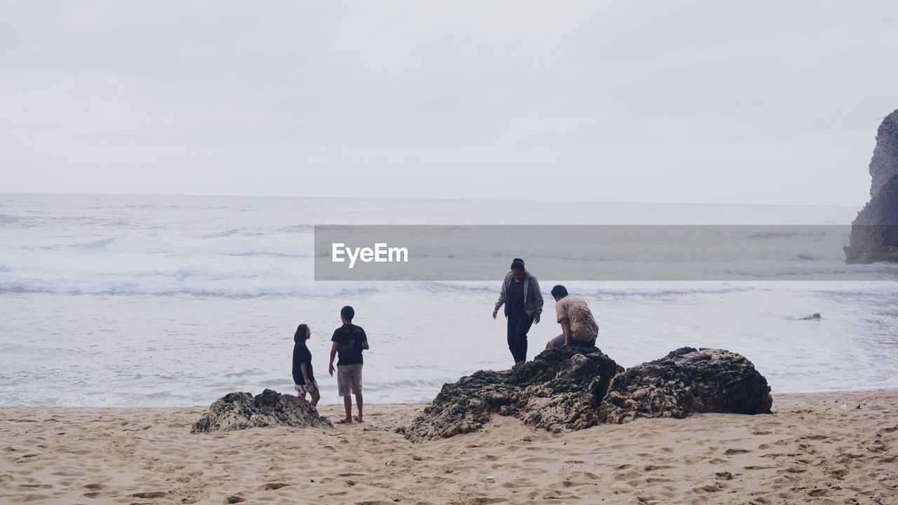 beach, sea, water, land, sky, ocean, coast, shore, nature, body of water, sand, men, adult, horizon over water, group of people, horizon, beauty in nature, rock, scenics - nature, full length, togetherness, women, leisure activity, holiday, wave, day, trip, vacation, outdoors, animal, environment, tranquility, mammal, cloud, animal themes, travel, lifestyles, child, small group of people, overcast, female, copy space, travel destinations