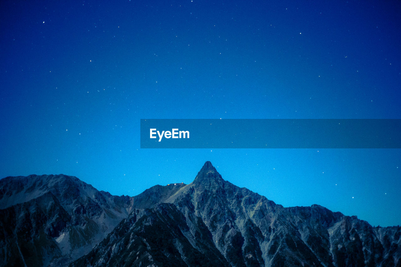 Scenic view of mountains against clear blue sky at night