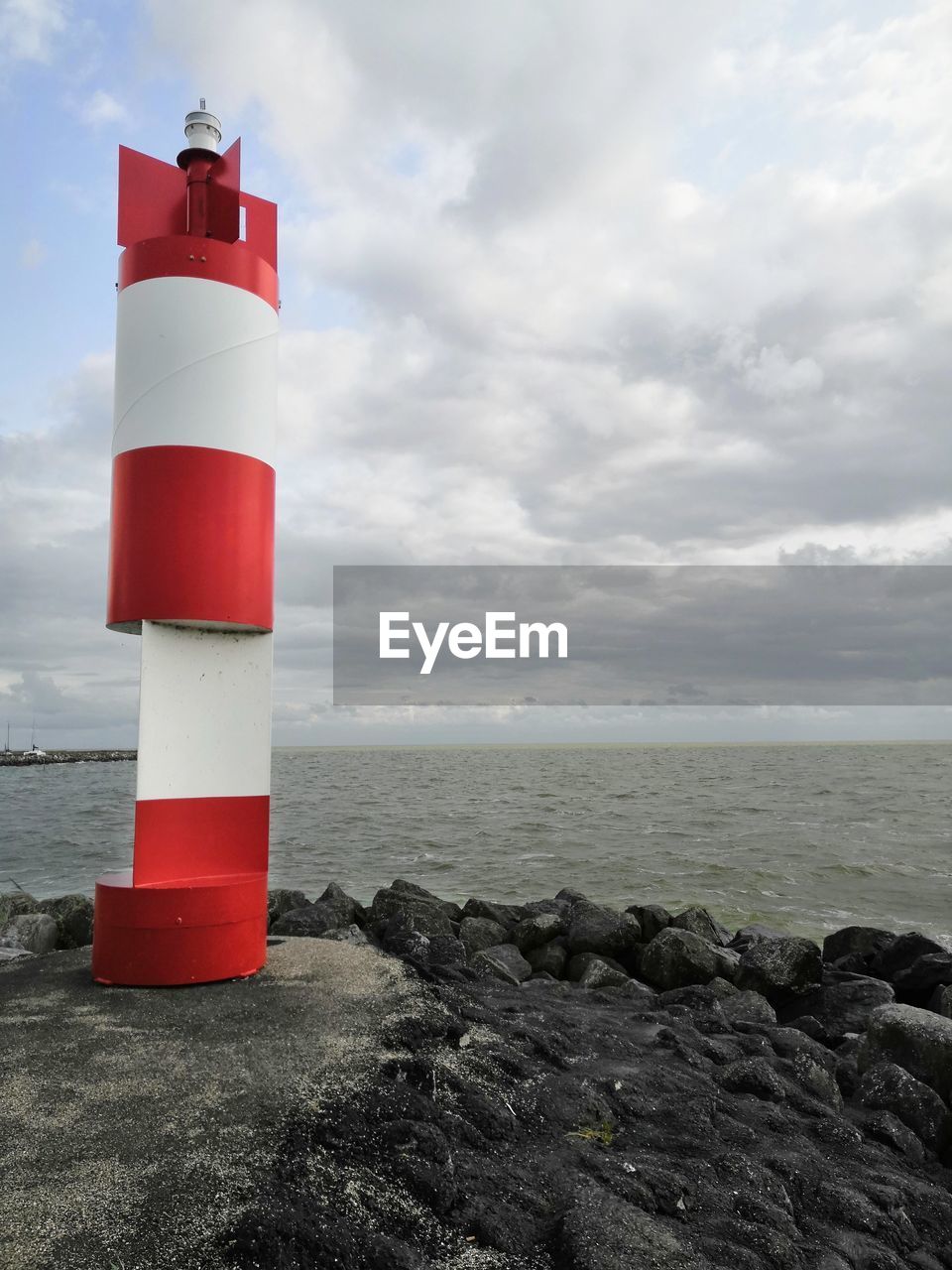 Red lighthouse by sea against sky