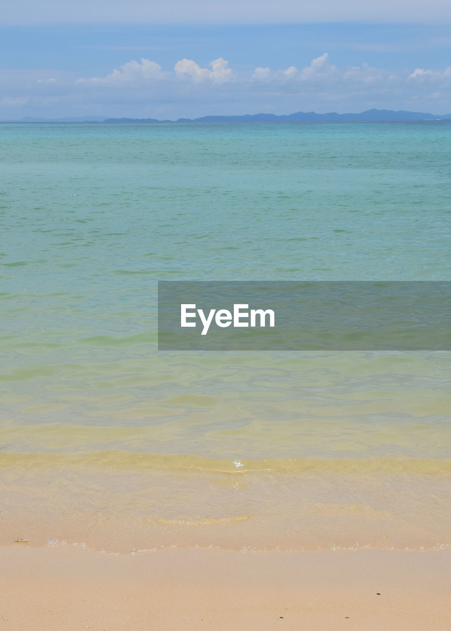 Scenic view of beach against cloudy sky