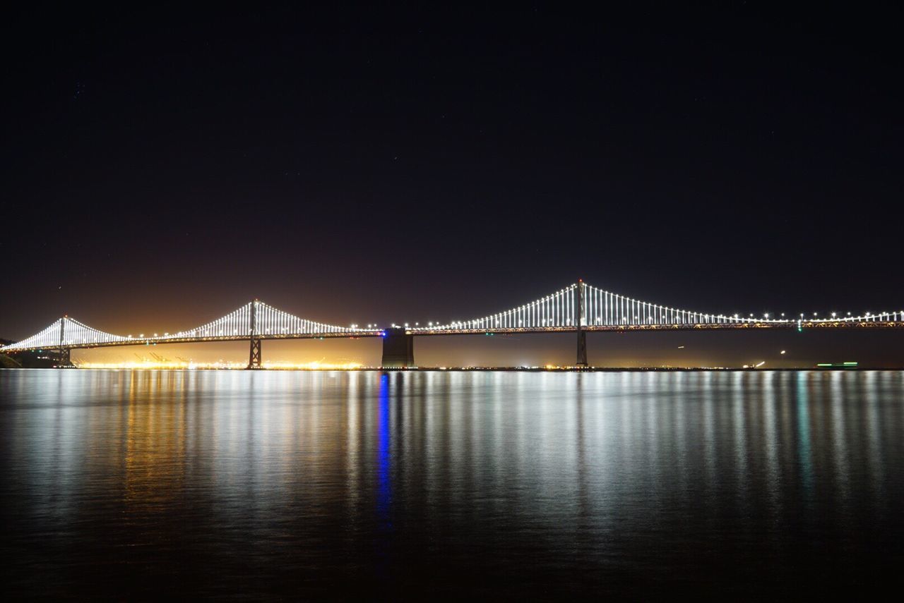 Illuminated oakland bay bridge over san francisco bay against clear sky at night