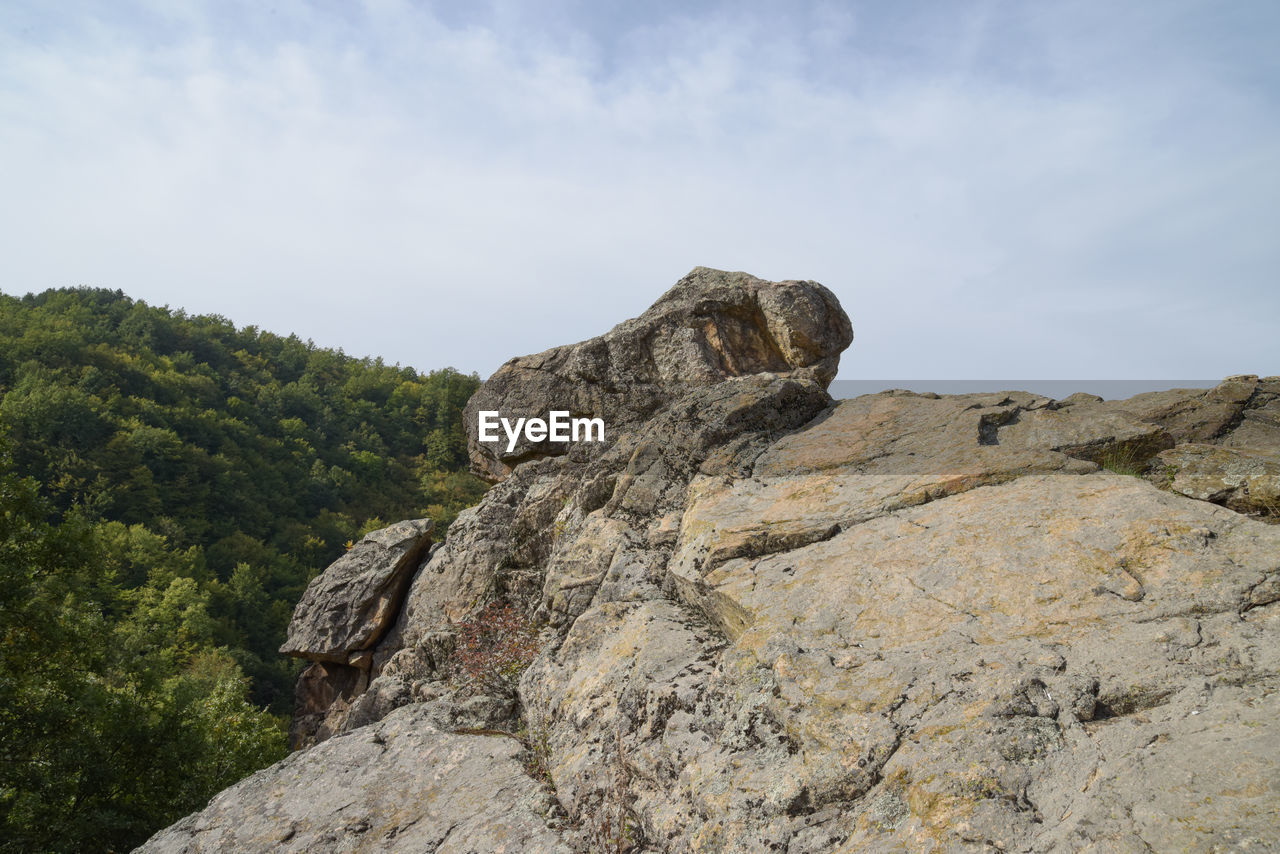 Low angle view of rocks on mountain against sky