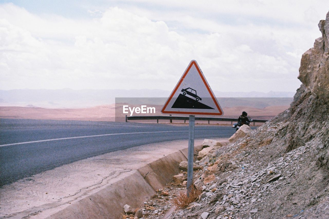 VIEW OF ROAD SIGN ON LANDSCAPE AGAINST MOUNTAIN RANGE