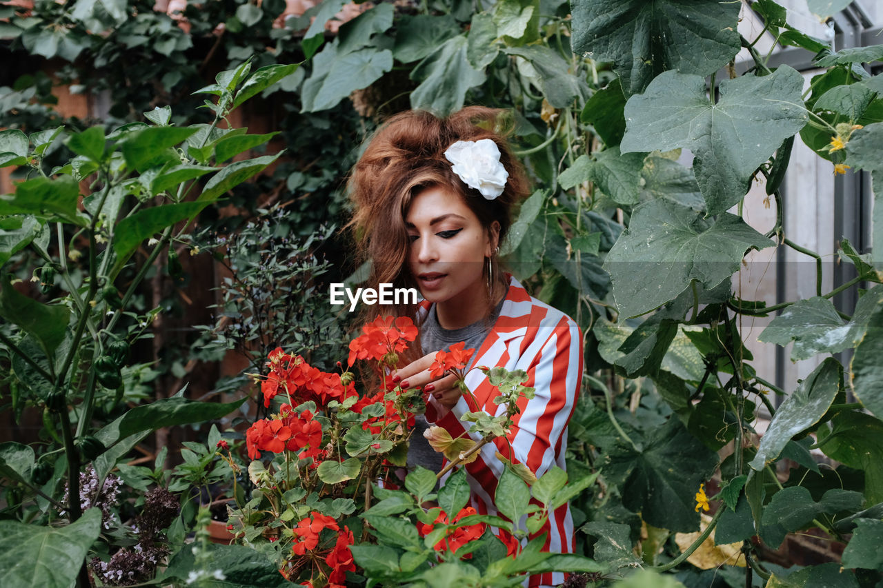 PORTRAIT OF BEAUTIFUL YOUNG WOMAN STANDING AGAINST PLANTS