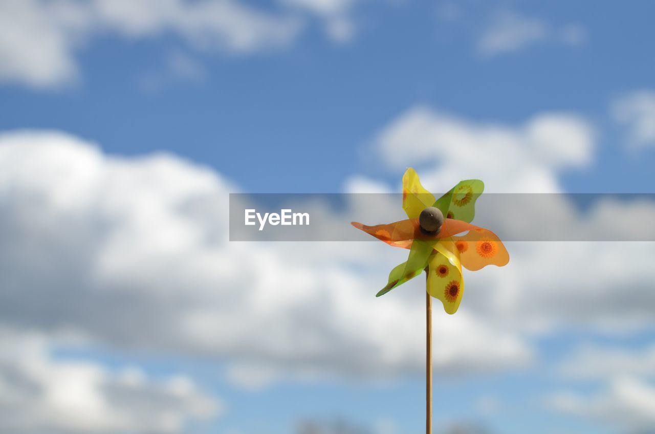 Low angle view of pinwheel against cloudy sky