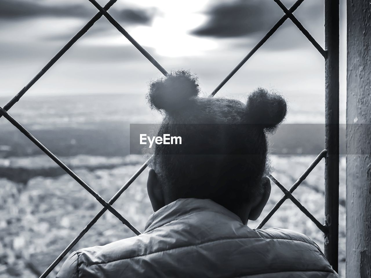 Rear view of woman by fence against sky