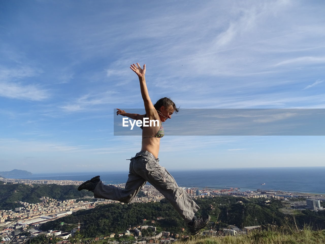 Energetic woman leaping in mid-air against sky