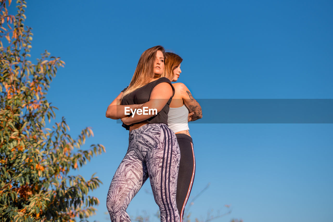 Low angle view of women in sports clothing against clear sky