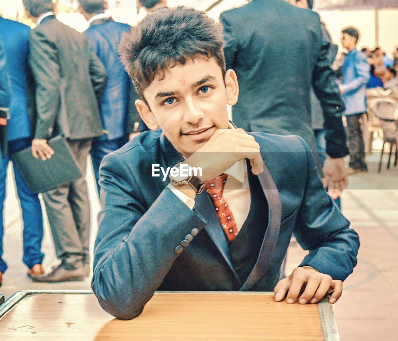 Portrait of teenage boy wearing suit sitting at table