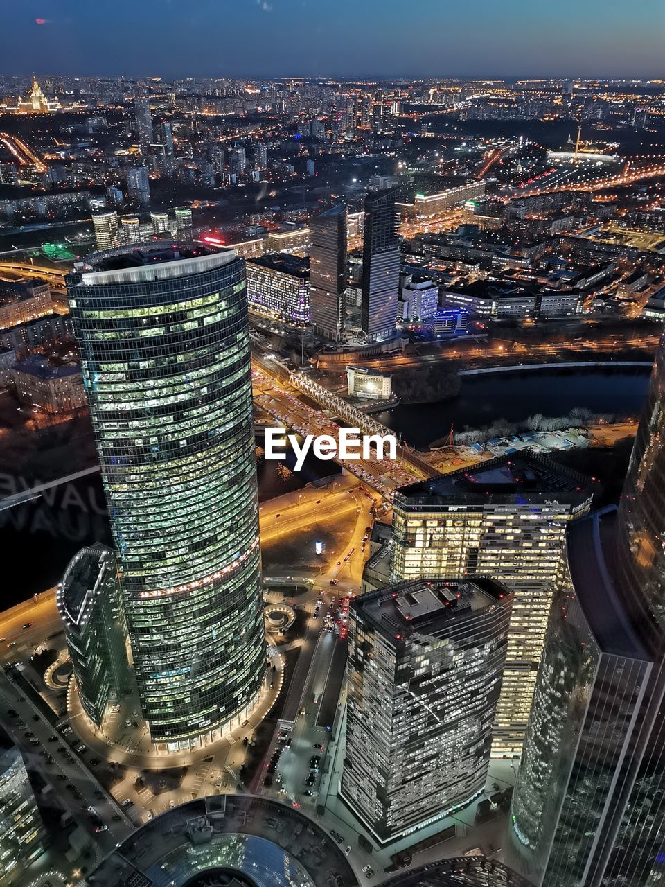 HIGH ANGLE VIEW OF ILLUMINATED CITY BUILDINGS AT NIGHT