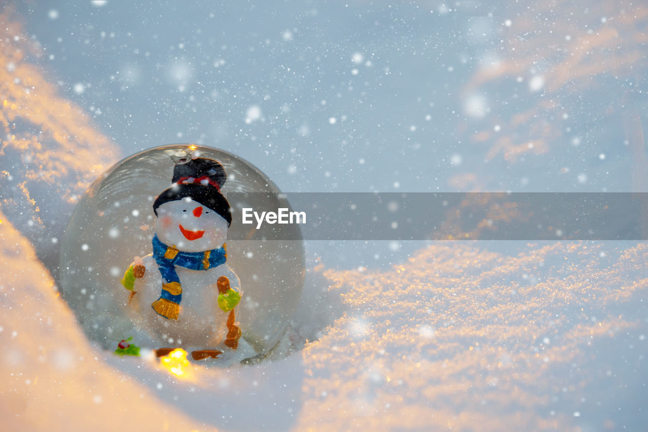 Glass snowball with snowman in the snow. winter concept. christmas and new year card