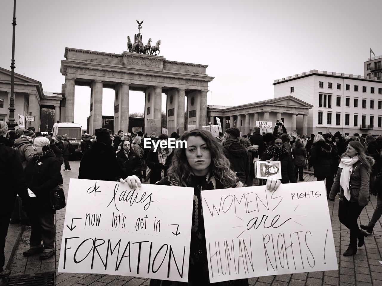 Woman holding banners with crowd against brandenburg gate