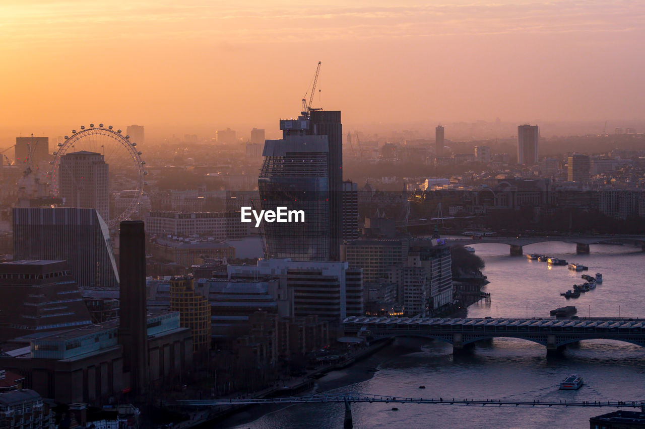 Modern buildings in city against sky during sunset