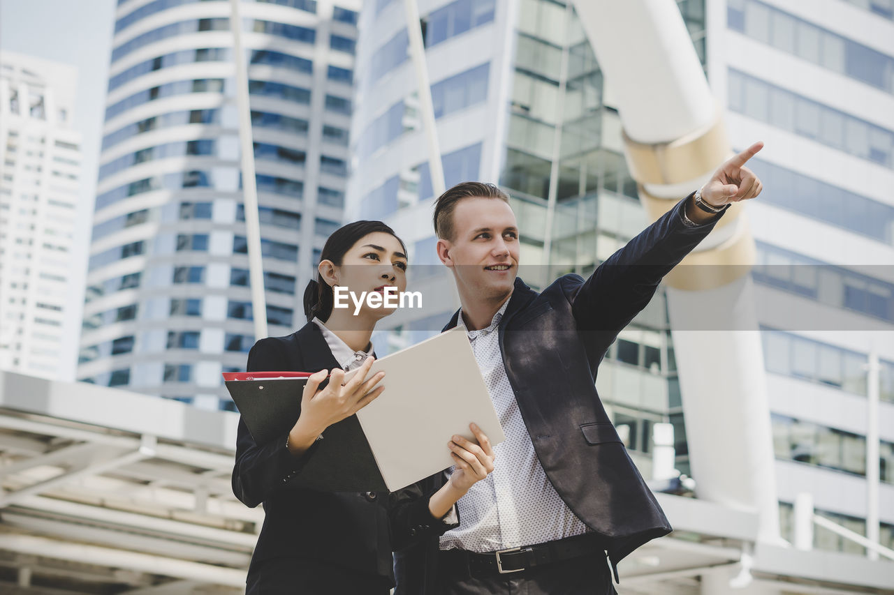 Low angle view of business people discussing while standing against building