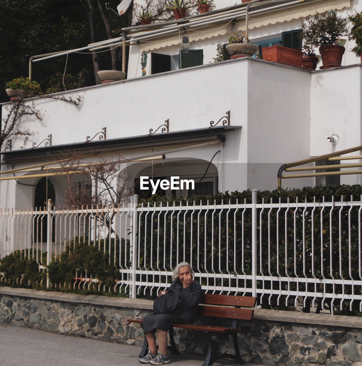 MAN SITTING IN BUILDING AGAINST BUILDINGS