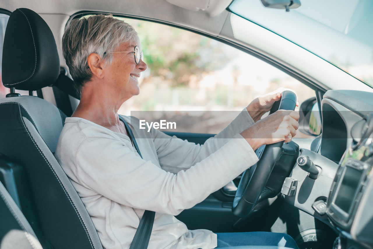 side view of woman using mobile phone while sitting in car