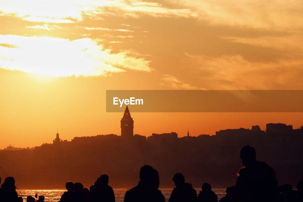 SILHOUETTE OF PEOPLE AGAINST BUILDING DURING SUNSET