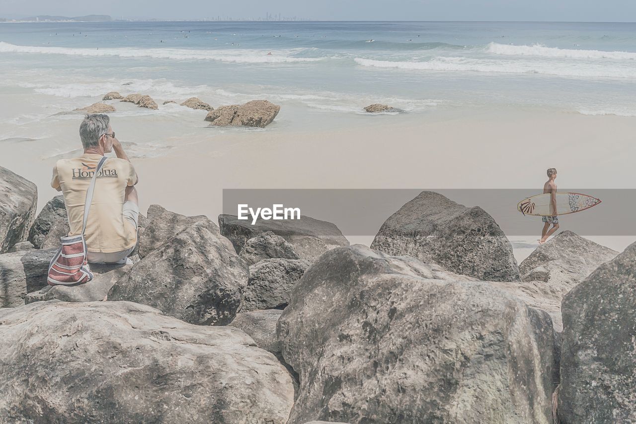 MAN PHOTOGRAPHING WOMAN ON BEACH