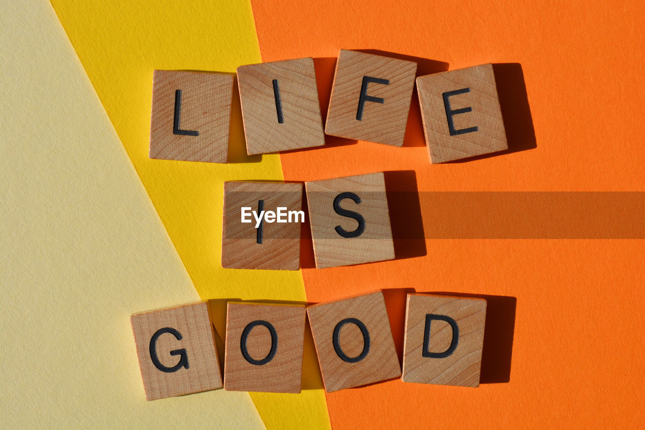 Life is good, motivational words in wooden alphabet letters isolated on orange and yellow background