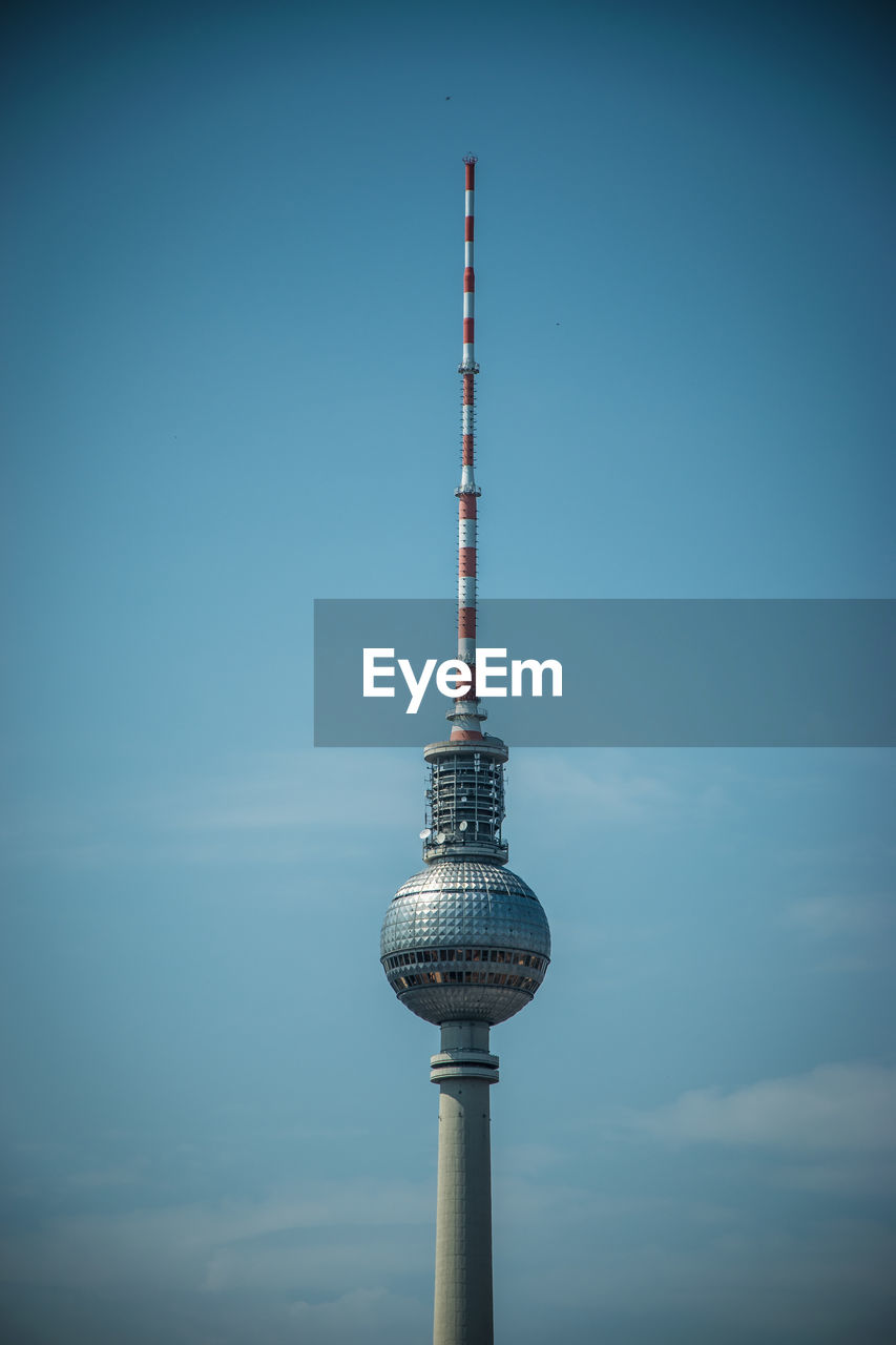 Low angle view of fernsehturm against blue sky in city