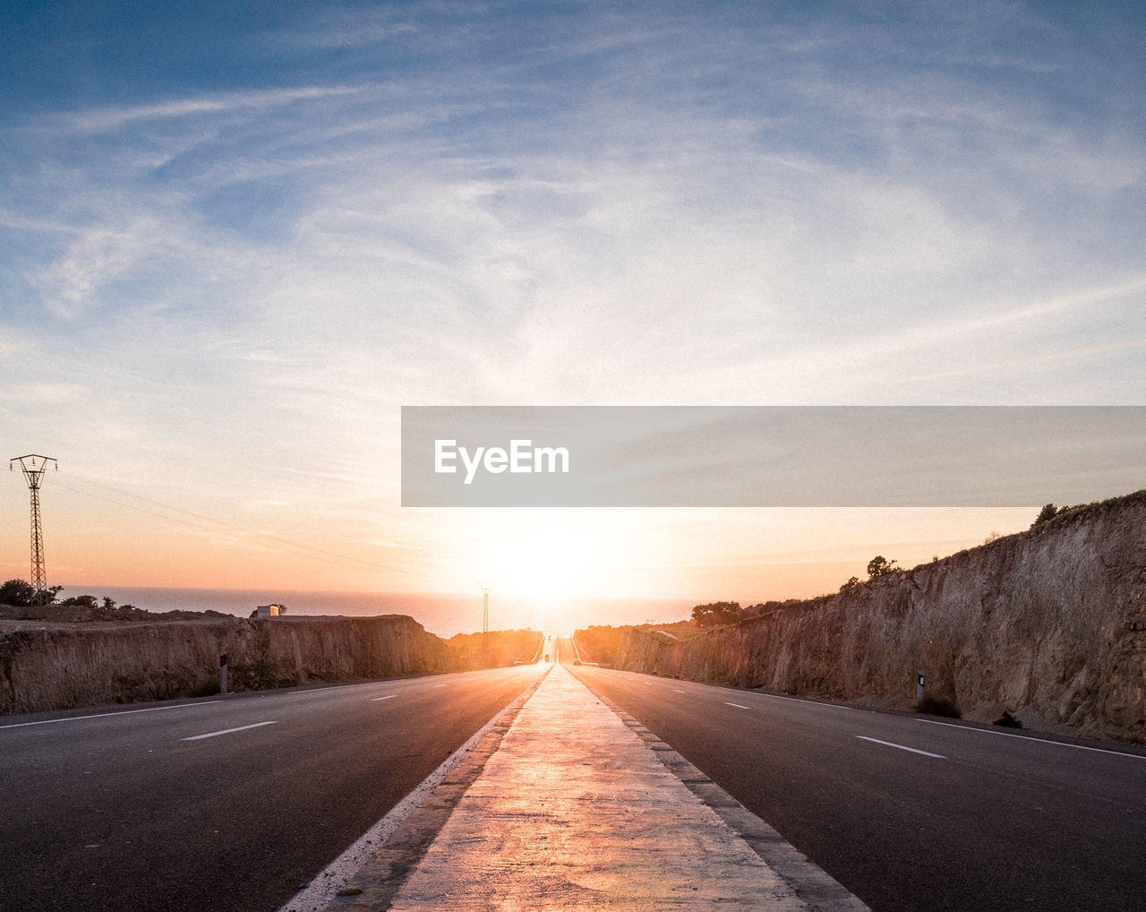 Road leading towards city against sky during sunset