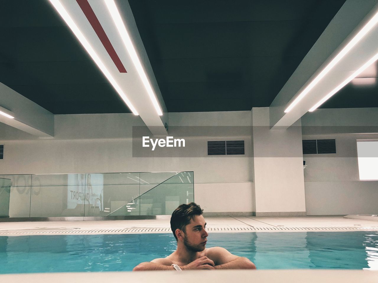 PORTRAIT OF YOUNG MAN SITTING IN SWIMMING POOL