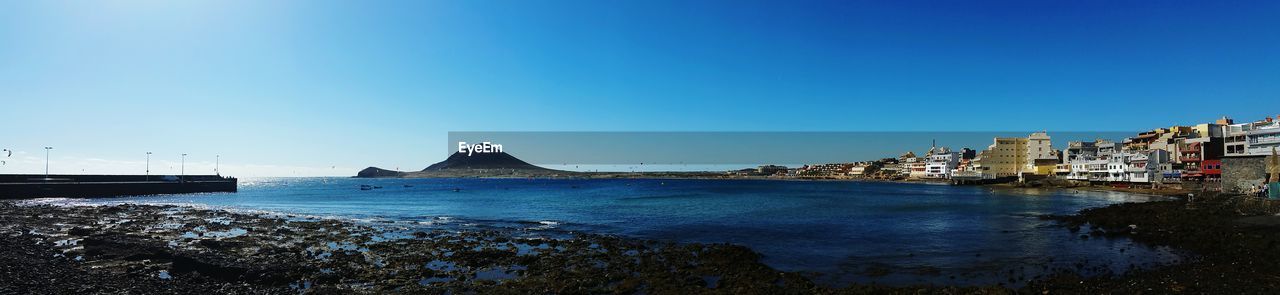 SCENIC VIEW OF SEA BY CITY AGAINST CLEAR SKY