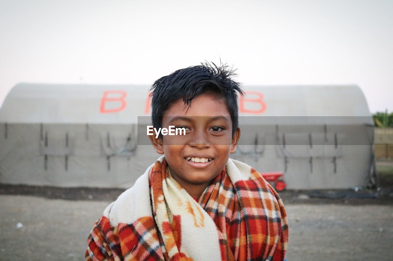 PORTRAIT OF SMILING BOY WITH TEXT AGAINST SKY