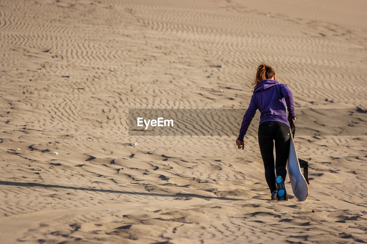 FULL LENGTH REAR VIEW OF WOMAN WALKING ON BEACH