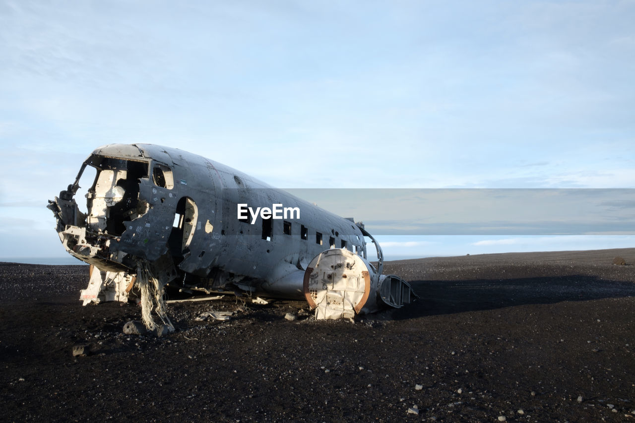 Damaged airplane on beach against sky