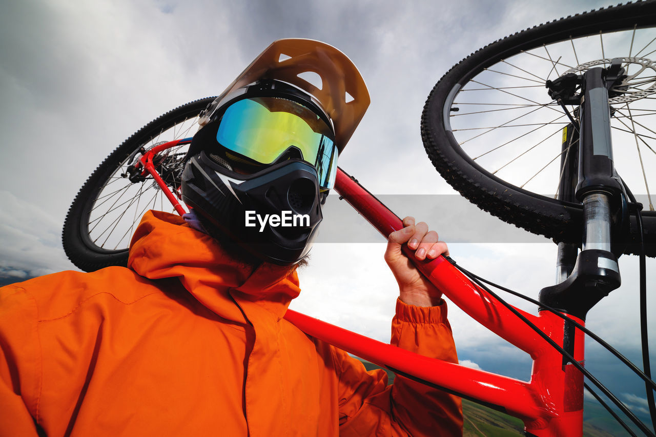 Wide angle vertical frame top angle. portrait of a bearded mountain biker with his bicycle against a