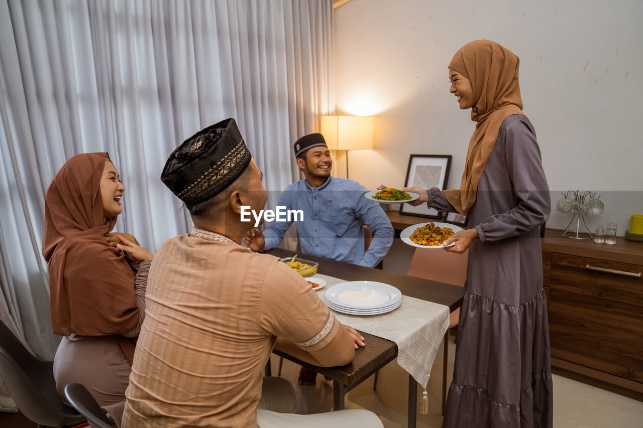 Smiling woman serving food to guests at home