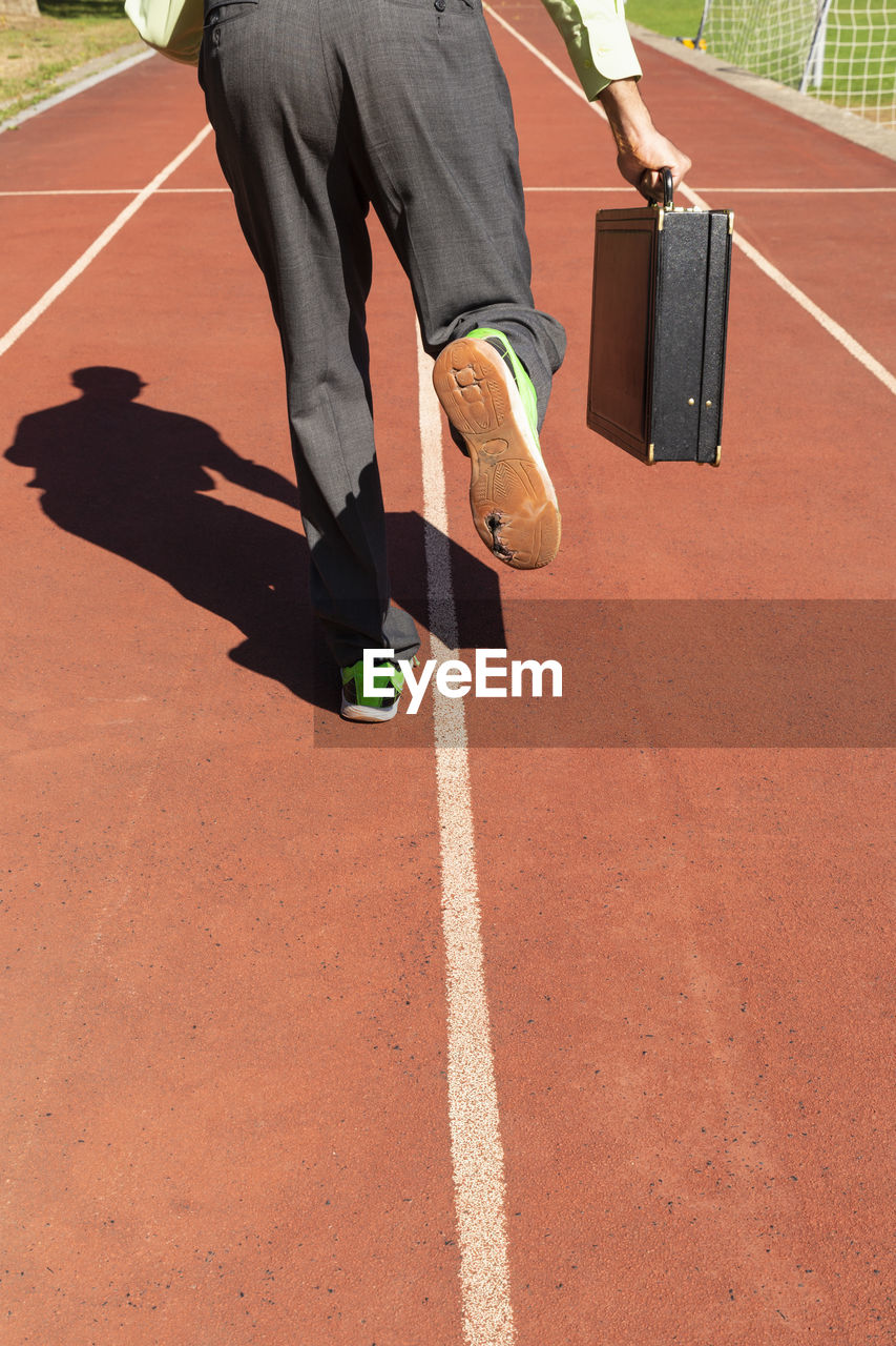 LOW SECTION VIEW OF MAN RUNNING ON STREET