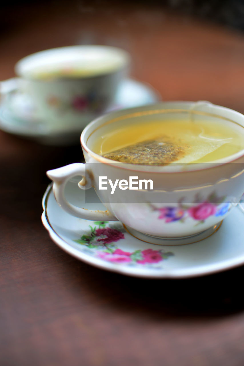 Close-up of tea cup on table and its reflection on a mirror