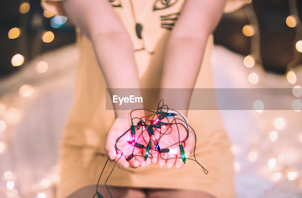 Midsection of woman with illuminated string lights