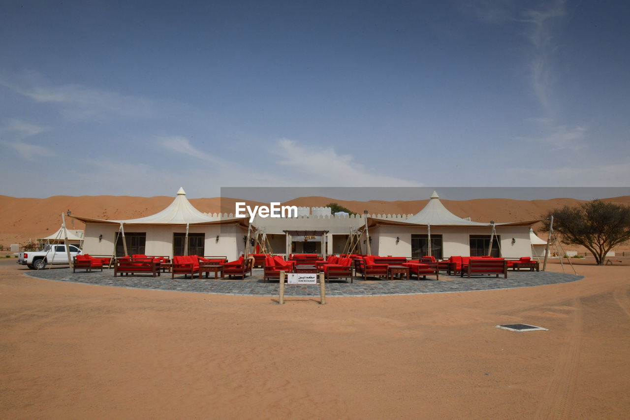 BEACH HUTS BY BUILDINGS AGAINST SKY